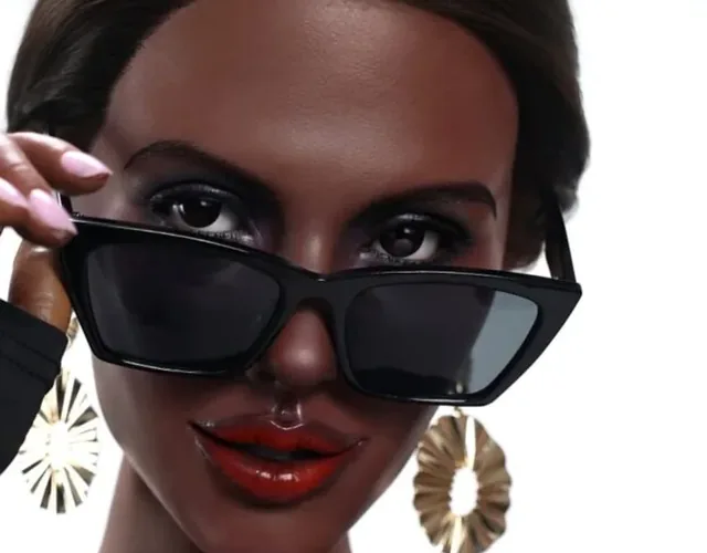 Dark-skinned doll lowering black sunglasses, with gold earrings